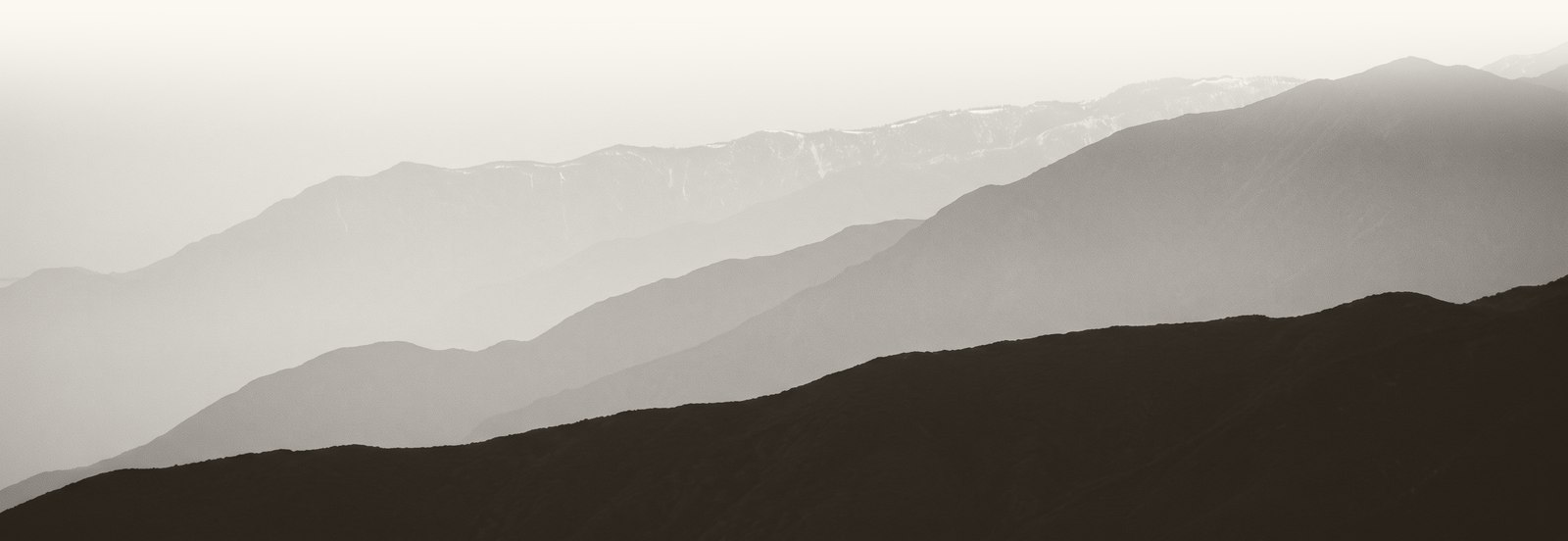 The San Gabriel Mountains seen from the Cucamonga valley floor, ridgelines receding into haze.